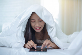 A beautiful asian woman relaxes and works with a laptop computer, reading at home. Free Photo
