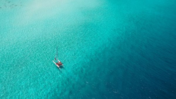 A catamaran sails across a shallow reef in the Maldives A catamaran sails across a shallow reef in the Maldives
