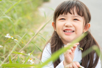 A cute girl is posing happily in the park  