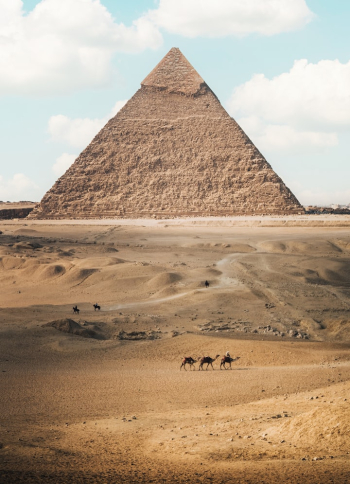 a group of people riding camels in front of a pyramid a group of people riding camels in front of a pyramid