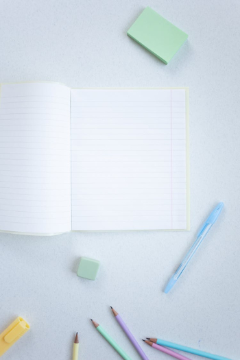 A Notebook and Coloring Materials on a White Surface