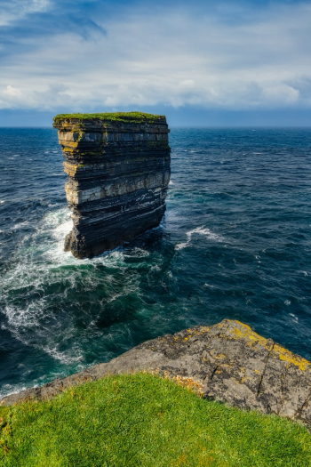 A Rock Formation with Green Grass Surrounded by the Sea A Rock Formation with Green Grass Surrounded by the Sea