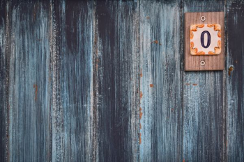 A weathered wooden wall with a small plaque with the number zero A weathered wooden wall with a small plaque with the number zero