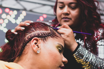 A woman braiding another woman A woman braiding another woman