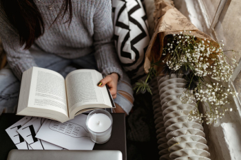 A woman in a sweater reads a book