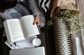 A woman in a sweater reads a book