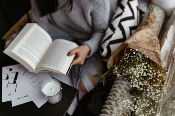 A woman in a sweater reads a book