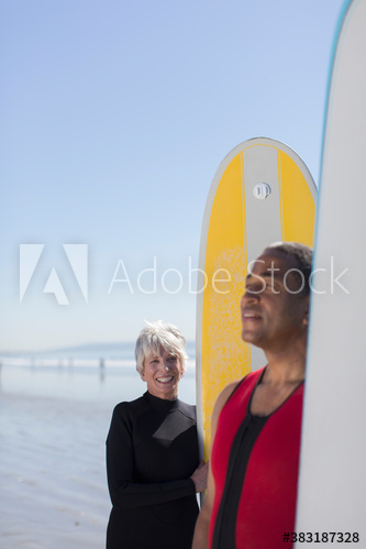 Active senior couple with surfboards on sunny beach Active senior couple with surfboards on sunny beach