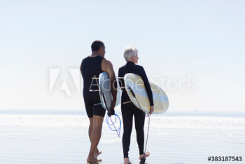 Active senior couple with surfboards on sunny beach Active senior couple with surfboards on sunny beach