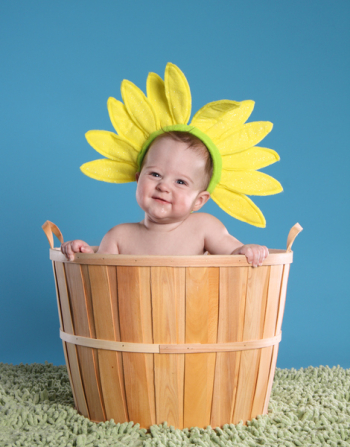 Adorable baby in a bushel basket wearing a flower headbandSEE