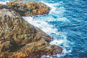 aerial photo of sea waves splashing through rocky mountain aerial photo of sea waves splashing through rocky mountain