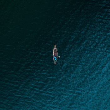 aerial photography of person riding boat on body of water aerial photography of person riding boat on body of water