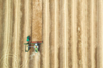aerial view photography of tractor with disc harrow attachment on grass field