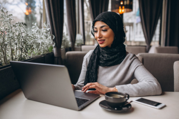 Arabian woman in hijab inside a cafe working on laptop Free Photo