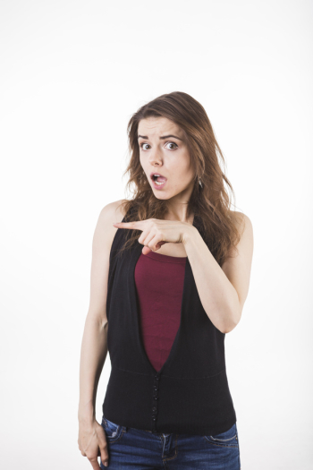 Astonished young woman pointing at something isolated on white backdrop