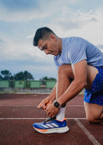 Athletic Man Tying Running Shoes at Track
