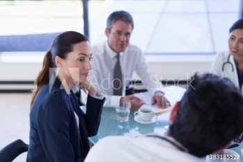 Attentive hospital administrator listening to doctors in meeting Attentive hospital administrator listening to doctors in meeting