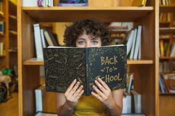 Back to school concept with girl reading book in library