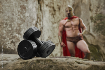Background of black metal dumbbells composed on rock with blurry background of muscular bodybuilder wearing armor of ancient gladiator.