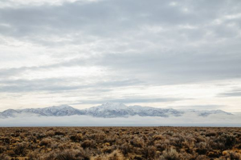 barren field across mountain range photo during cloudy day barren field across mountain range photo during cloudy day