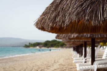 Beach Loungers under Thatches by the Sea Beach Loungers under Thatches by the Sea