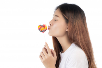 Beautiful woman with a happy smile holding a hand candy, isolated on white background.