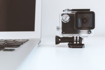 black action camera beside white laptop black action camera beside white laptop