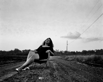 Black and White Photography of Woman on Chair on Road Black and White Photography of Woman on Chair on Road