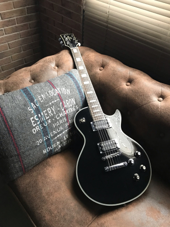 Black Guitar on Brown Leather Sofa Near Window Black Guitar on Brown Leather Sofa Near Window