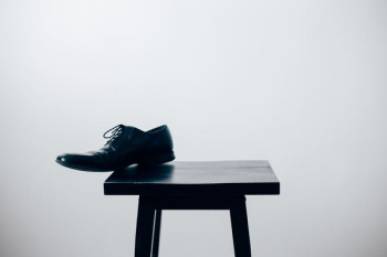 black leather dress shoe on black wooden table black leather dress shoe on black wooden table
