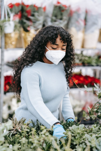 Black woman in medical mask choosing flowers