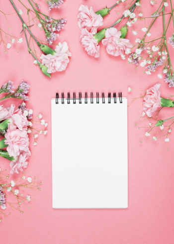 Blank spiral notepad decorated with carnations; gypsophila; limonium flowers on pink background