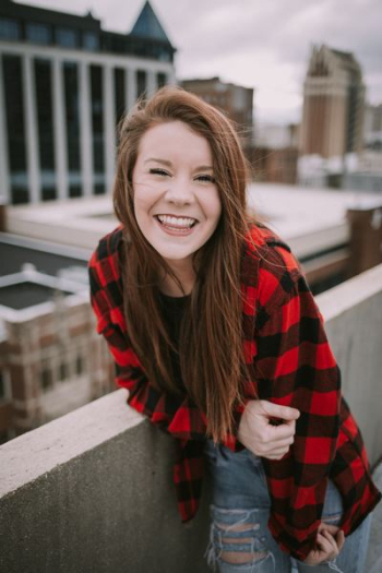 blonde wearing black and red plaid long-sleeve shirt smiling