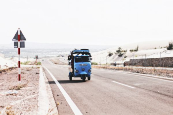 blue auto-rickshaw beside road signage blue auto-rickshaw beside road signage