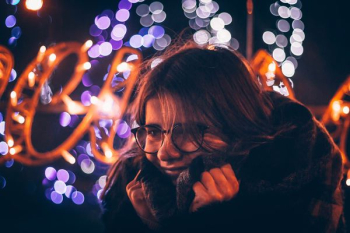 bokeh photography of woman holding coat wearing eyeglasses