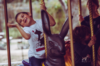 Boy in White T-shirt Riding Carousel Boy in White T-shirt Riding Carousel
