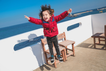 Boy Jumping Near Brown Wooden Chairs Boy Jumping Near Brown Wooden Chairs