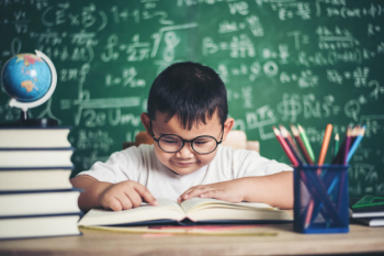 boy reading a book sitting at the table in the classroom boy reading a book sitting at the table in the classroom