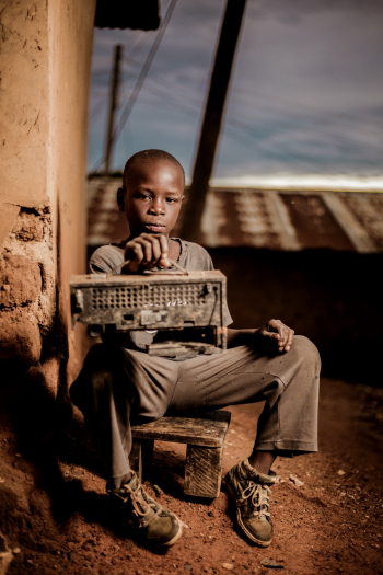 Boy Sitting Beside Wall