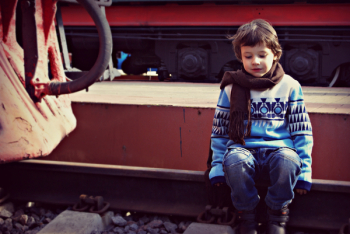 Boy Sitting on Train Rail