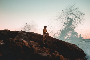 boy sitting with waves splashing