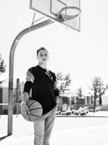 Boy Standing and Holding Basketball Under The Basketball Hoop Boy Standing and Holding Basketball Under The Basketball Hoop
