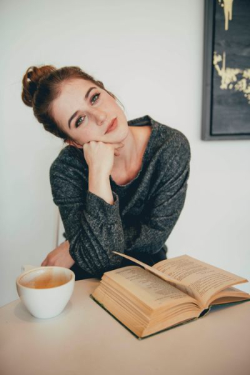 brown-haired woman in black sweater near brown book