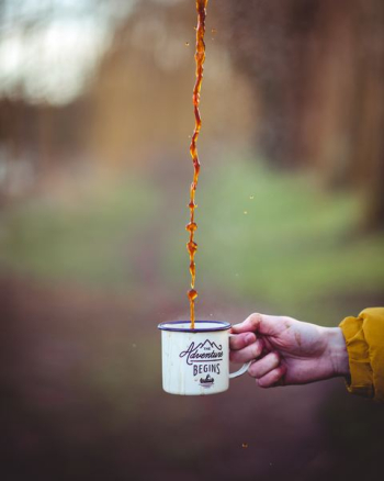 brown liquid poured on white enamel cup brown liquid poured on white enamel cup