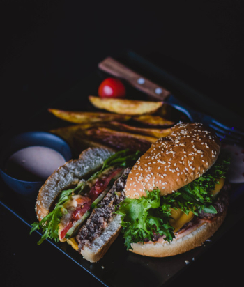 Burger With Green Leafy Vegetable and Cheese on Black Plate