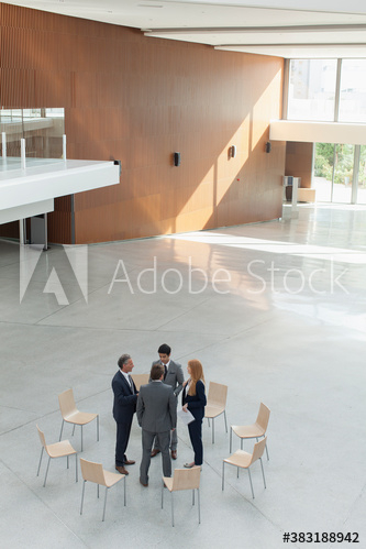 Business people talking in circle of chairs in modern lobby Business people talking in circle of chairs in modern lobby