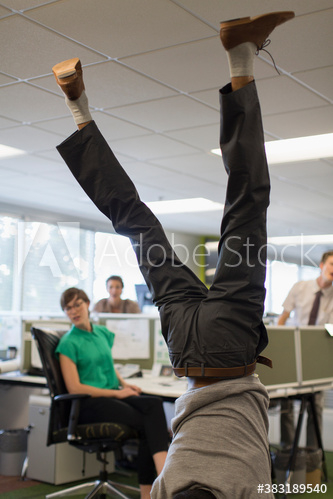 Businessman doing handstand in office Businessman doing handstand in office