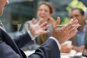 Businessman gesturing in meeting with colleagues Businessman gesturing in meeting with colleagues