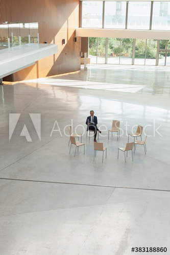 Businessman waiting in circle of chairs in modern lobby Businessman waiting in circle of chairs in modern lobby
