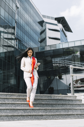 Businesswoman moving down staircase in front of building Businesswoman moving down staircase in front of building